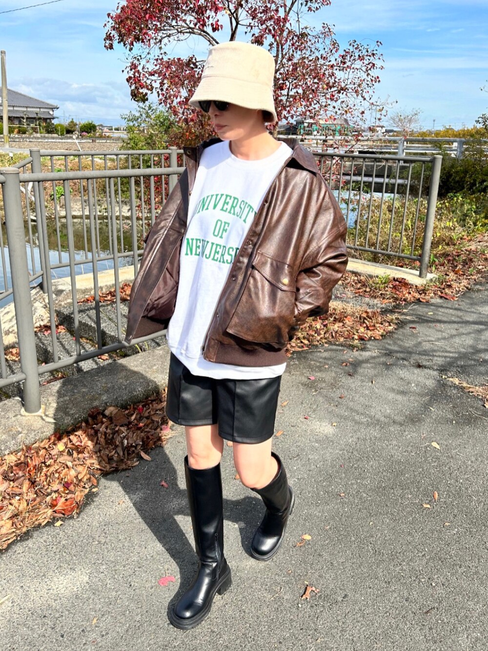 ブラウン系のブルゾン、ホワイト系のスウェット、ブラック系のパンツを着用したレディースの秋コーディネートの4枚目の写真