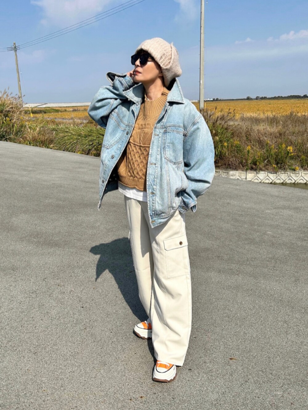 ホワイト系のパンツ、ブルー系のデニムジャケット、オレンジ系のスニーカーを着用したレディースの秋コーディネートの3枚目の写真
