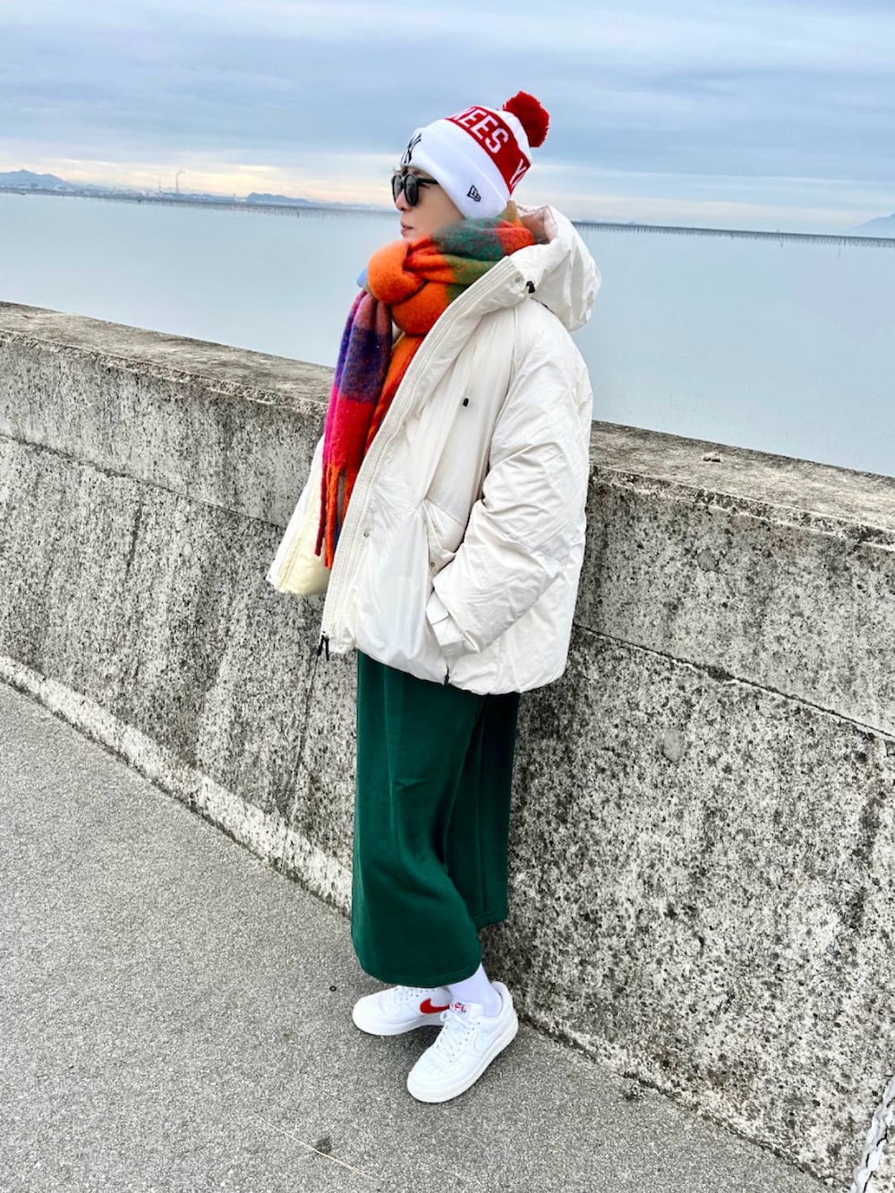 ホワイト系のダウンジャケット/コート、ホワイト系のスニーカー、グリーン系のワンピースを着用したレディースの冬コーディネートの3枚目の写真