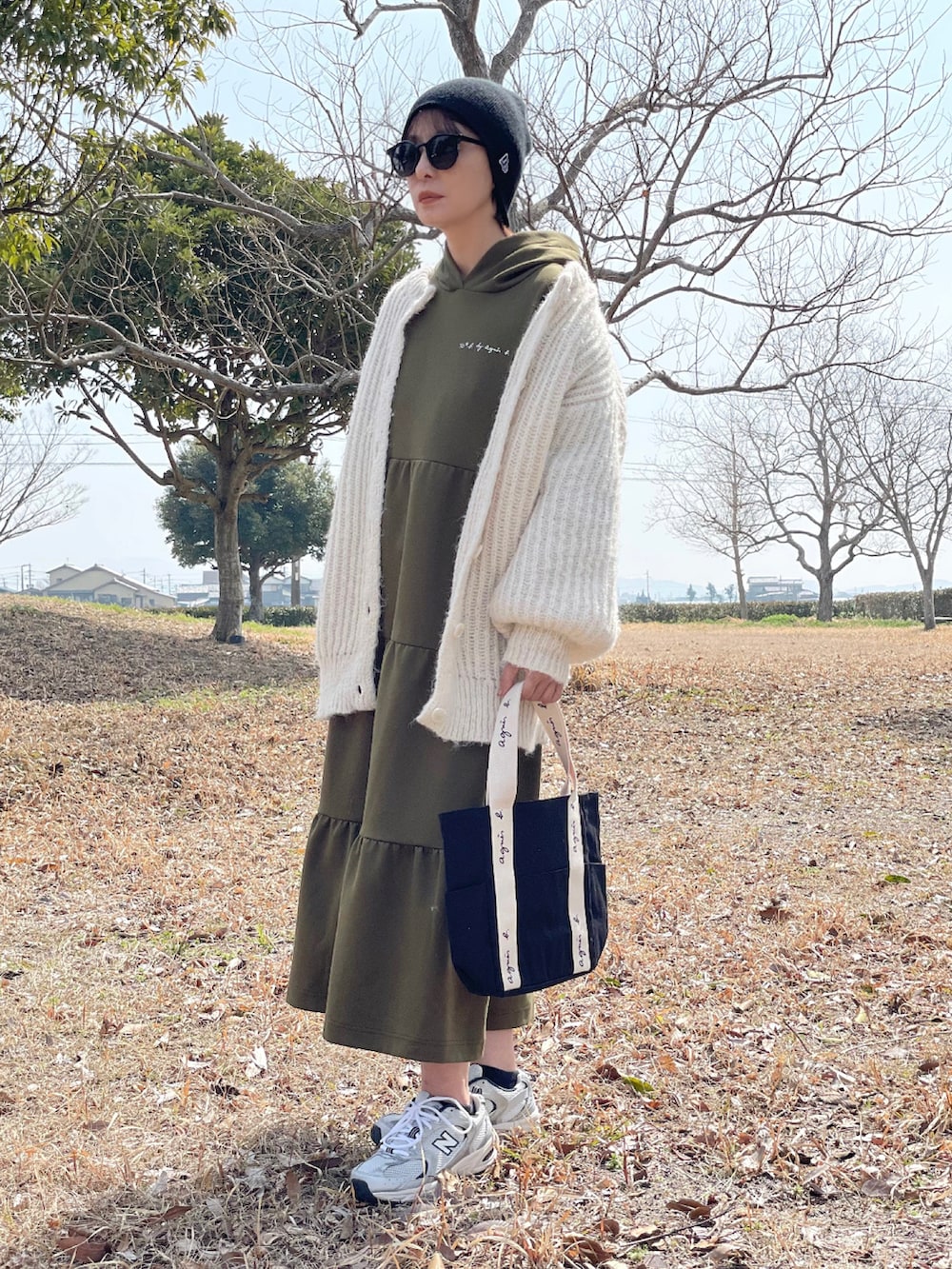 グリーン系のワンピース、ブラック系のトートバッグ、シルバー系のスニーカーを着用したレディースの春コーディネートの3枚目の写真