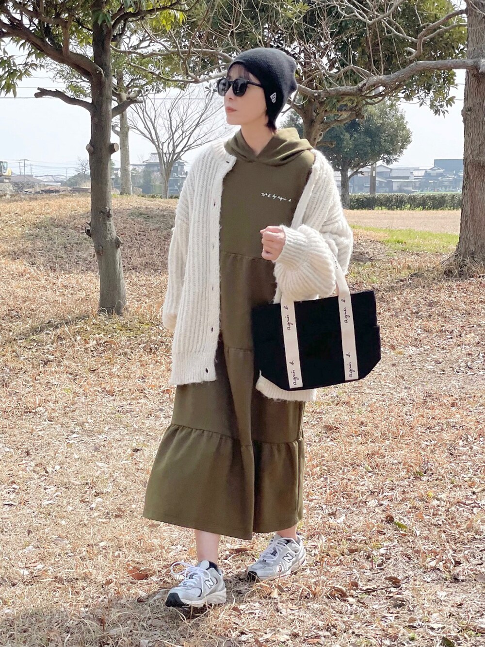 グリーン系のワンピース、ブラック系のトートバッグ、シルバー系のスニーカーを着用したレディースの春コーディネートの2枚目の写真