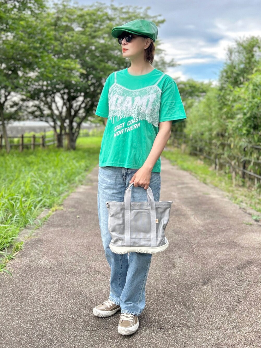 グレー系のトートバッグ、グリーン系のTシャツ/カットソー、ブルー系のデニムパンツを着用したレディースの春コーディネートの5枚目の写真