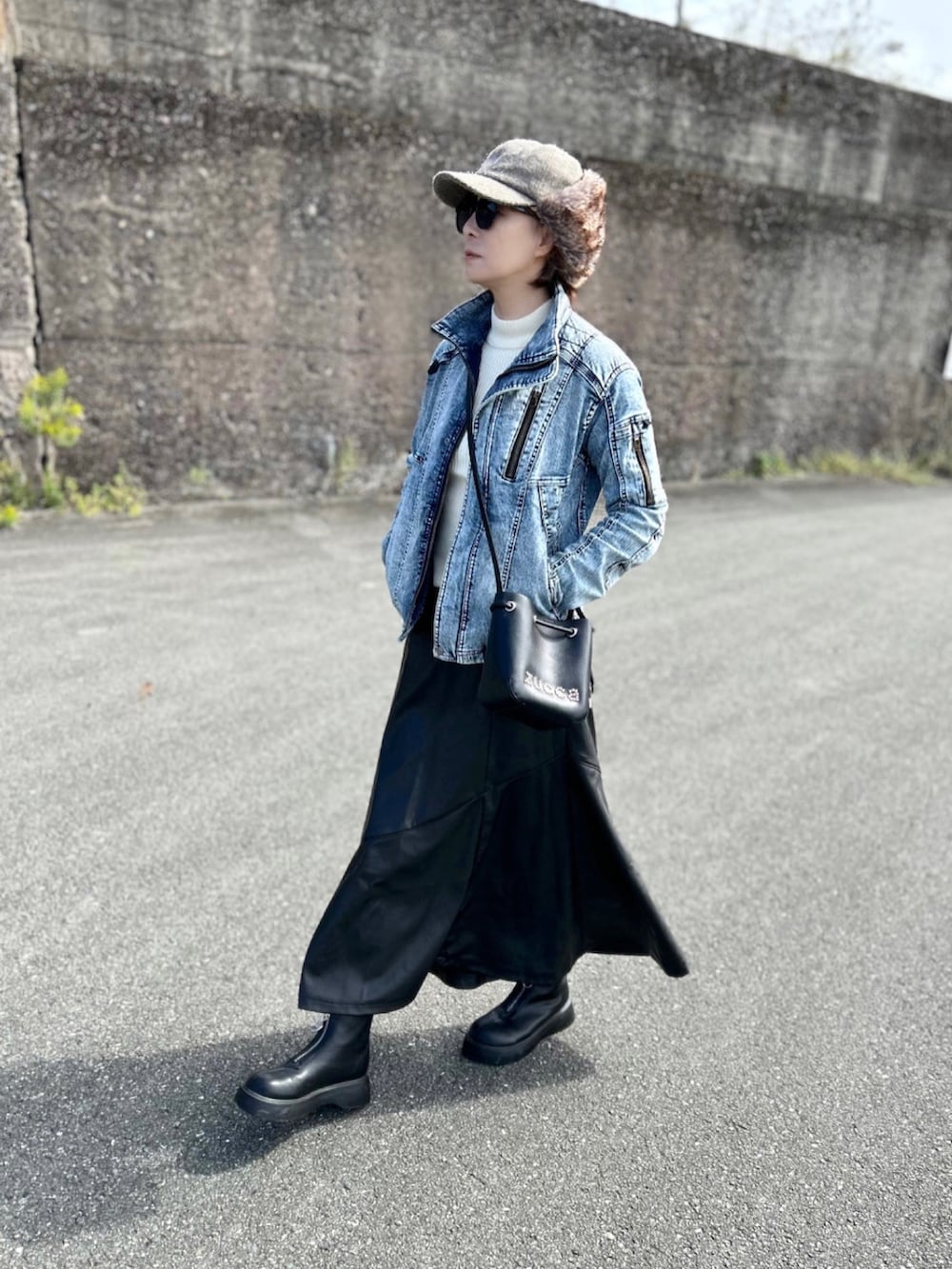 ブルー系のデニムジャケット、ブラック系のスカート、ブラック系のブーツを着用したレディースの秋コーディネートの2枚目の写真