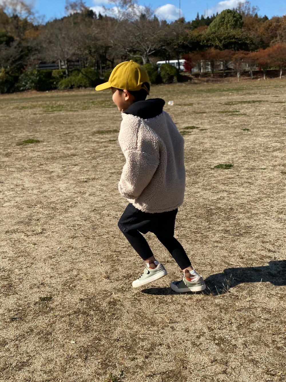 ベージュ系のノーカラージャケット、ホワイト系のパーカー、ブラック系のパンツを着用したキッズの秋コーディネートの2枚目の写真