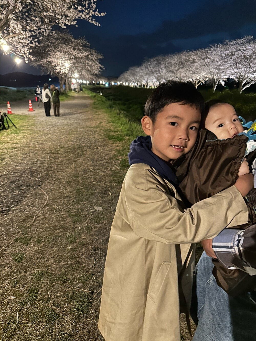 グレー系のパーカー、ベージュ系のノーカラーコート、ブルー系のデニムパンツを着用したキッズの春コーディネートの3枚目の写真