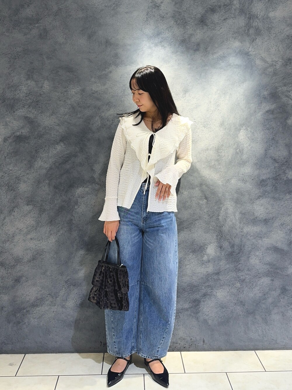 ホワイト系のTシャツ/カットソー、ブルー系のデニムパンツ、ブラック系のハンドバッグを着用したレディースの秋コーディネートの3枚目の写真