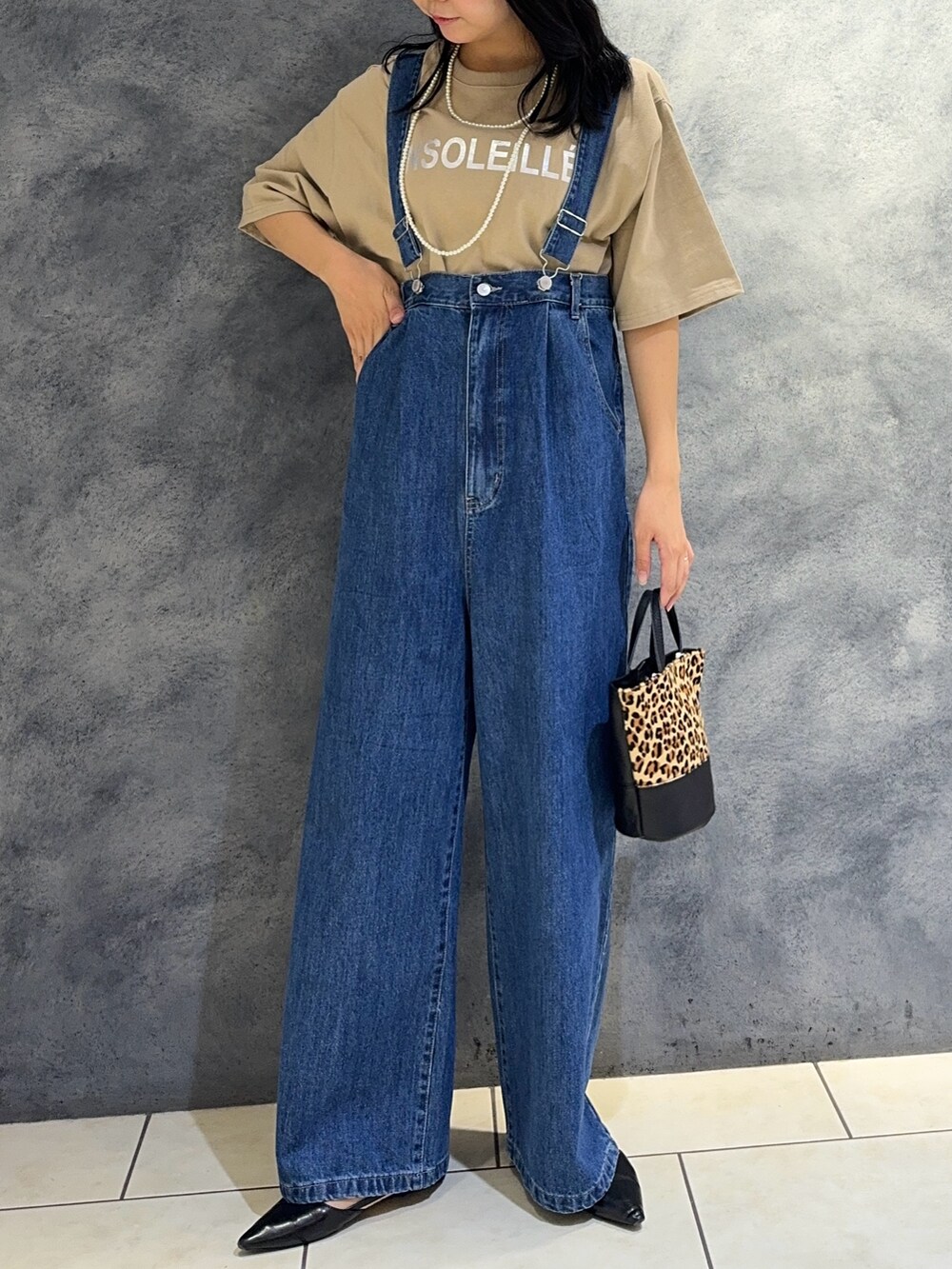 ブルー系のデニムパンツ、ベージュ系のTシャツ/カットソー、ベージュ系のショルダーバッグを着用したレディースの夏コーディネートの2枚目の写真