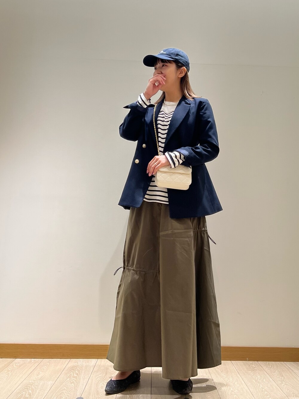 グリーン系のスカート、ブラック系のTシャツ/カットソー、ホワイト系のショルダーバッグを着用したレディースの春コーディネートの2枚目の写真