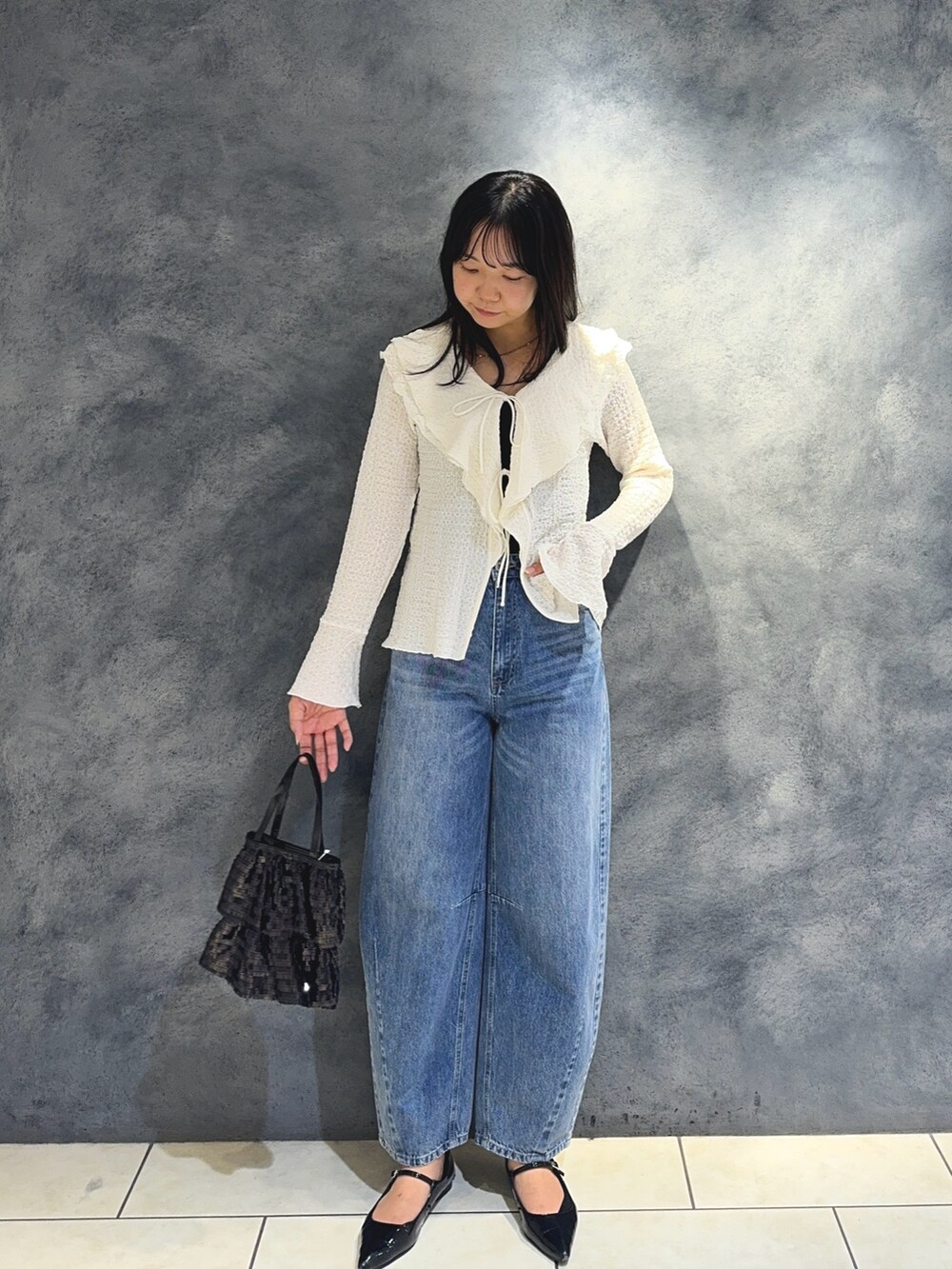 ホワイト系のTシャツ/カットソー、ブルー系のデニムパンツ、ブラック系のハンドバッグを着用したレディースの秋コーディネートの5枚目の写真