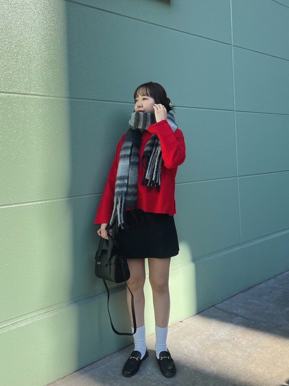 レッド系のニット/セーター、ブラック系のその他パンツ、ブラック系のストール/ショールを着用したレディースの冬コーディネートの2枚目の写真