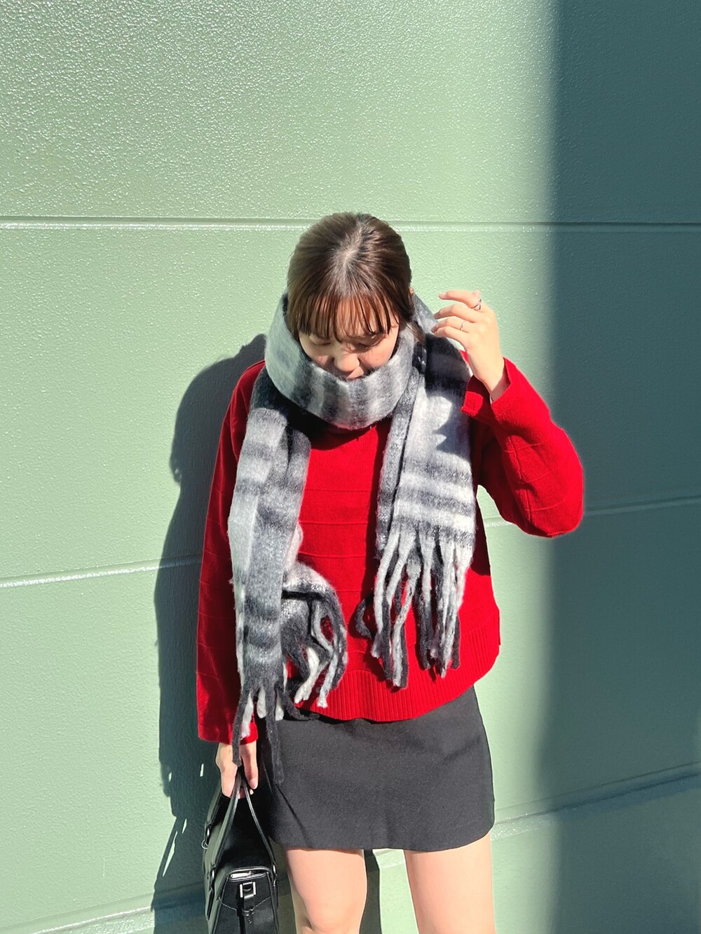 レッド系のニット/セーター、ブラック系のその他パンツ、ブラック系のストール/ショールを着用したレディースの冬コーディネートの4枚目の写真