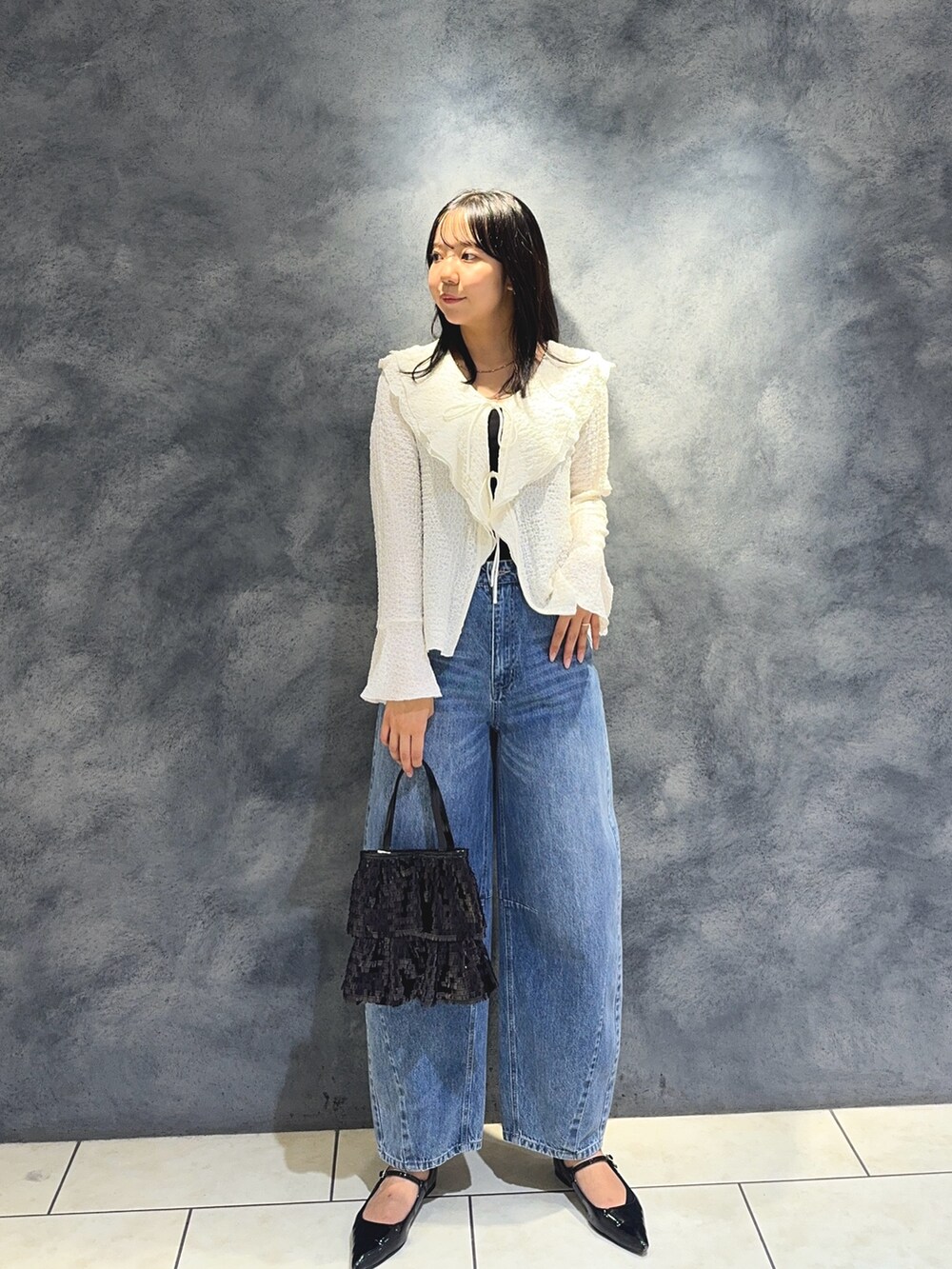 ホワイト系のTシャツ/カットソー、ブルー系のデニムパンツ、ブラック系のハンドバッグを着用したレディースの秋コーディネートの2枚目の写真