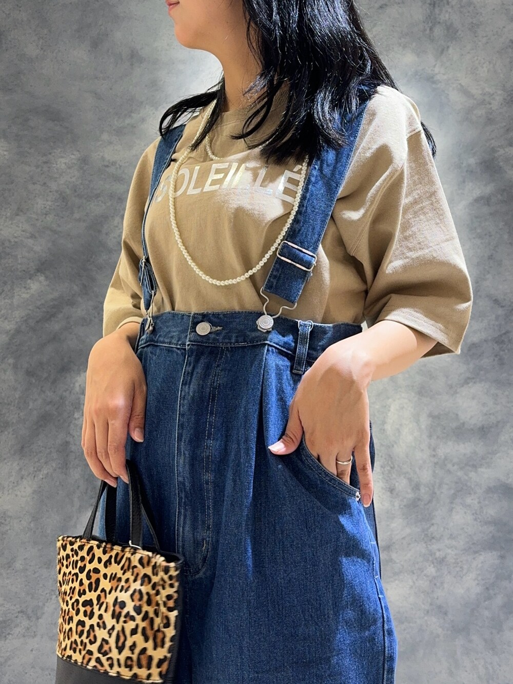 ブルー系のデニムパンツ、ベージュ系のTシャツ/カットソー、ベージュ系のショルダーバッグを着用したレディースの夏コーディネートの7枚目の写真