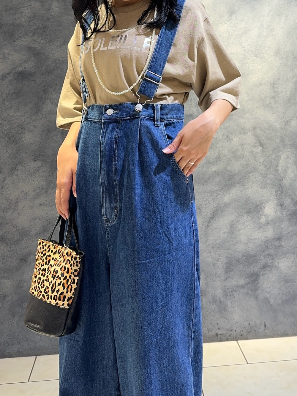 ブルー系のデニムパンツ、ベージュ系のTシャツ/カットソー、ベージュ系のショルダーバッグを着用したレディースの夏コーディネートの6枚目の写真