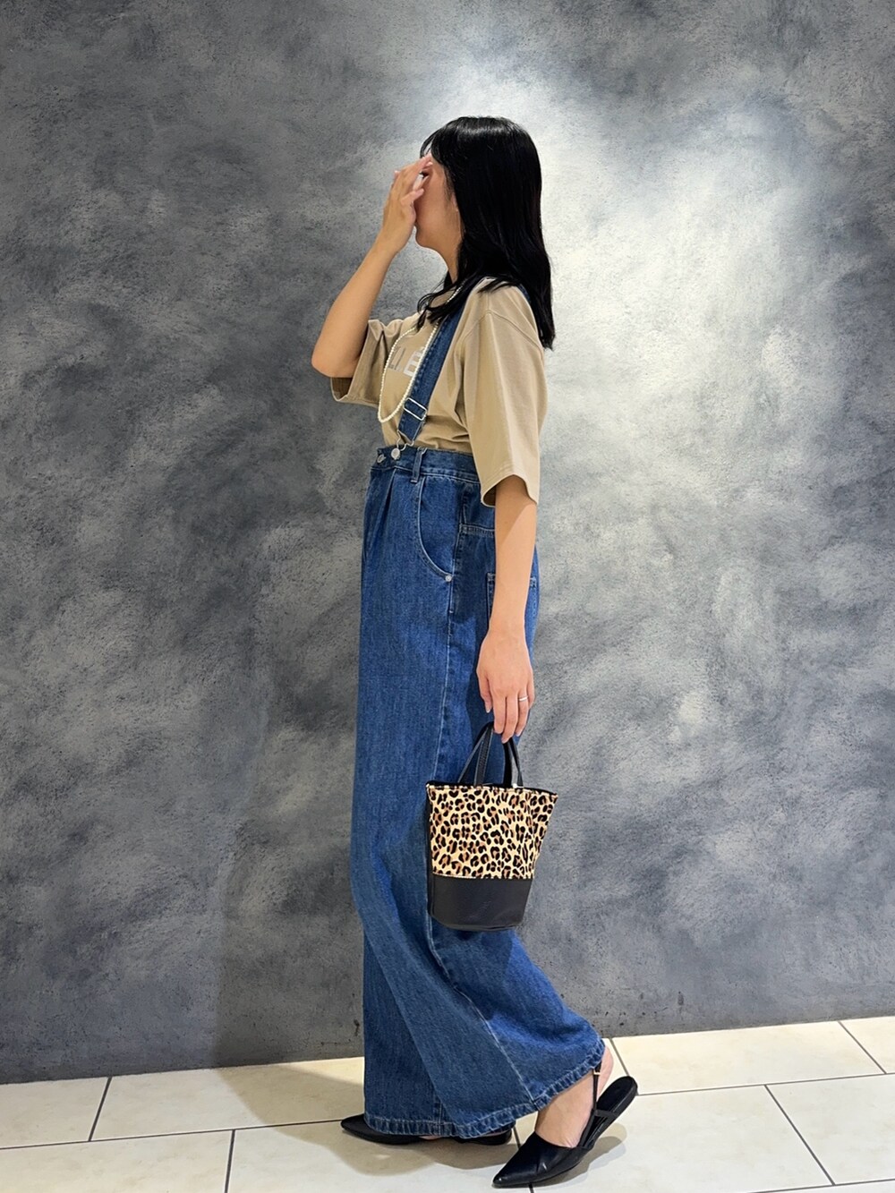 ブルー系のデニムパンツ、ベージュ系のTシャツ/カットソー、ベージュ系のショルダーバッグを着用したレディースの夏コーディネートの4枚目の写真