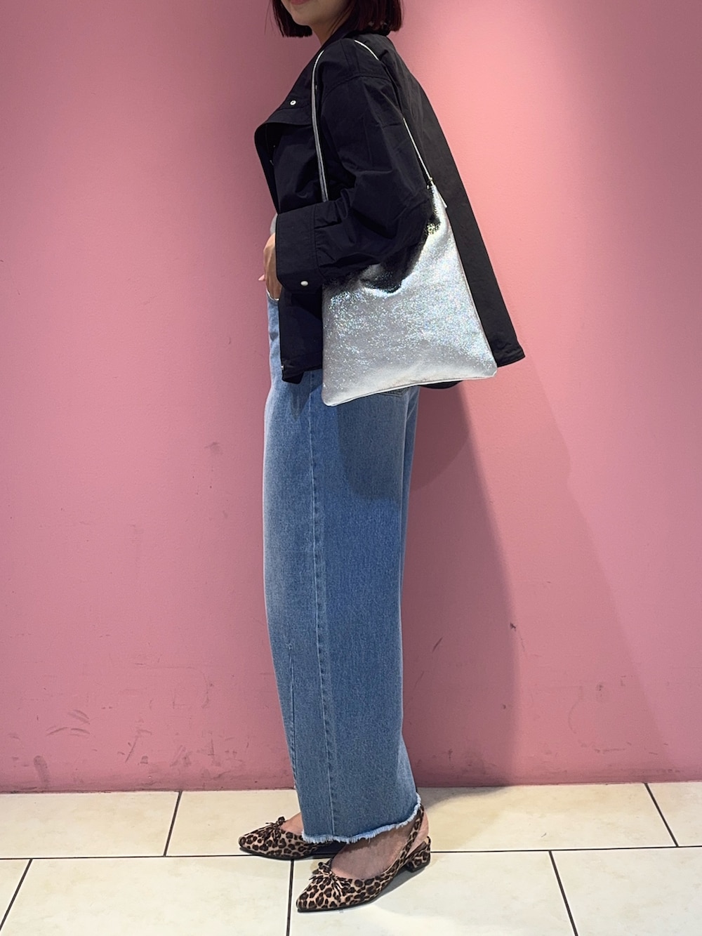 ブラック系のブルゾン、ブルー系のデニムパンツ、シルバー系のトートバッグを着用したレディースの春コーディネートの3枚目の写真