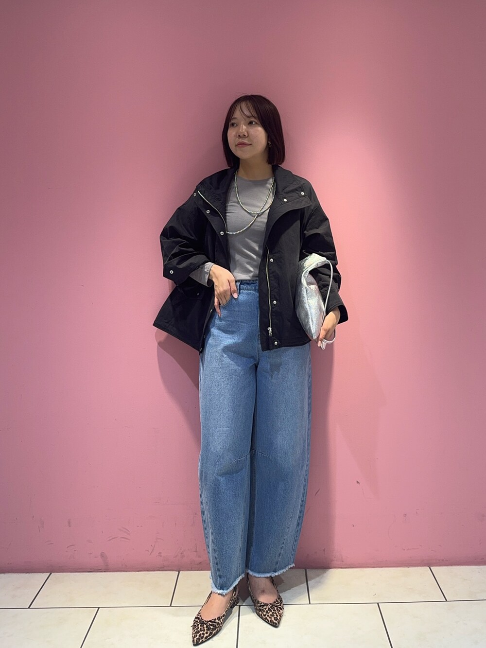 ブラック系のブルゾン、ブルー系のデニムパンツ、シルバー系のトートバッグを着用したレディースの春コーディネートの2枚目の写真