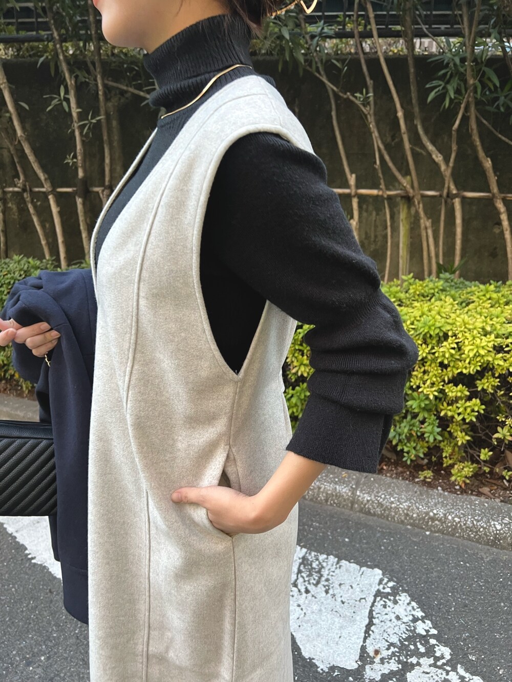 グレー系のワンピース、ブラック系のニット/セーター、ゴールド系のネックレスを着用したレディースの冬コーディネートの3枚目の写真