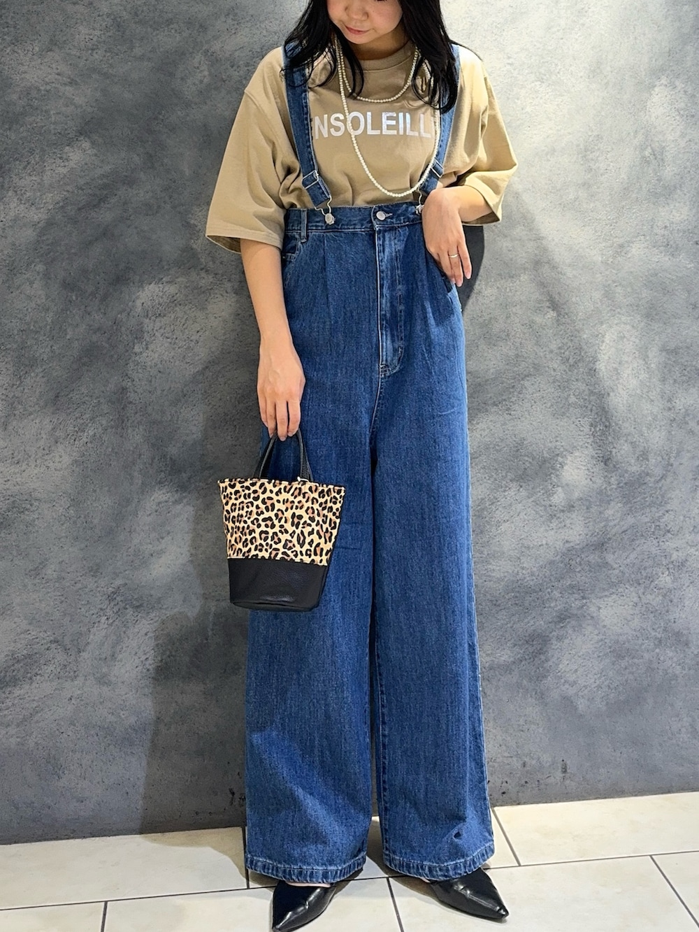 ブルー系のデニムパンツ、ベージュ系のTシャツ/カットソー、ベージュ系のショルダーバッグを着用したレディースの夏コーディネートの5枚目の写真