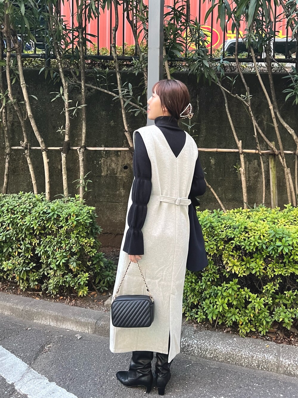 グレー系のワンピース、ブラック系のニット/セーター、ゴールド系のネックレスを着用したレディースの冬コーディネートの2枚目の写真