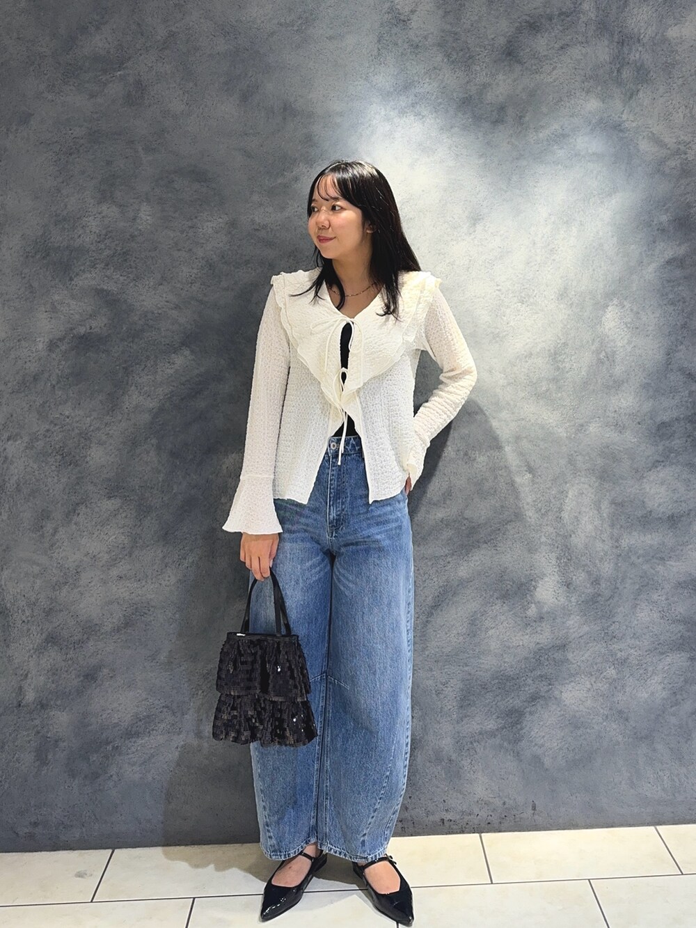 ホワイト系のTシャツ/カットソー、ブルー系のデニムパンツ、ブラック系のハンドバッグを着用したレディースの秋コーディネートの4枚目の写真