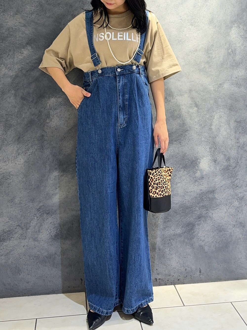 ブルー系のデニムパンツ、ベージュ系のTシャツ/カットソー、ベージュ系のショルダーバッグを着用したレディースの夏コーディネートの3枚目の写真