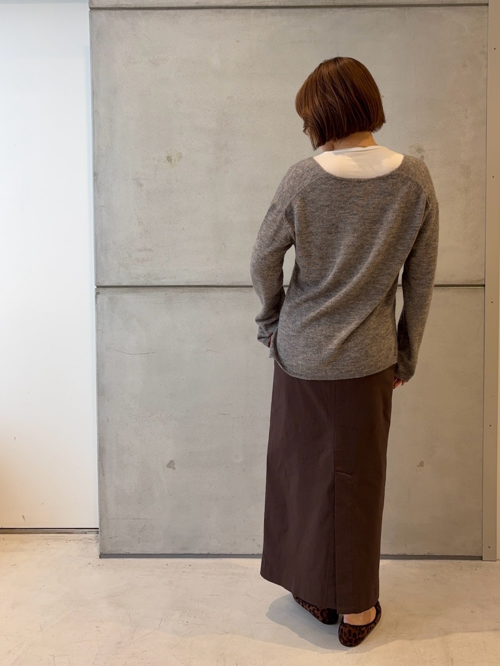 ホワイト系のTシャツ/カットソー、グレー系のニット/セーター、ブラウン系のスカートを着用したレディースの秋コーディネートの4枚目の写真