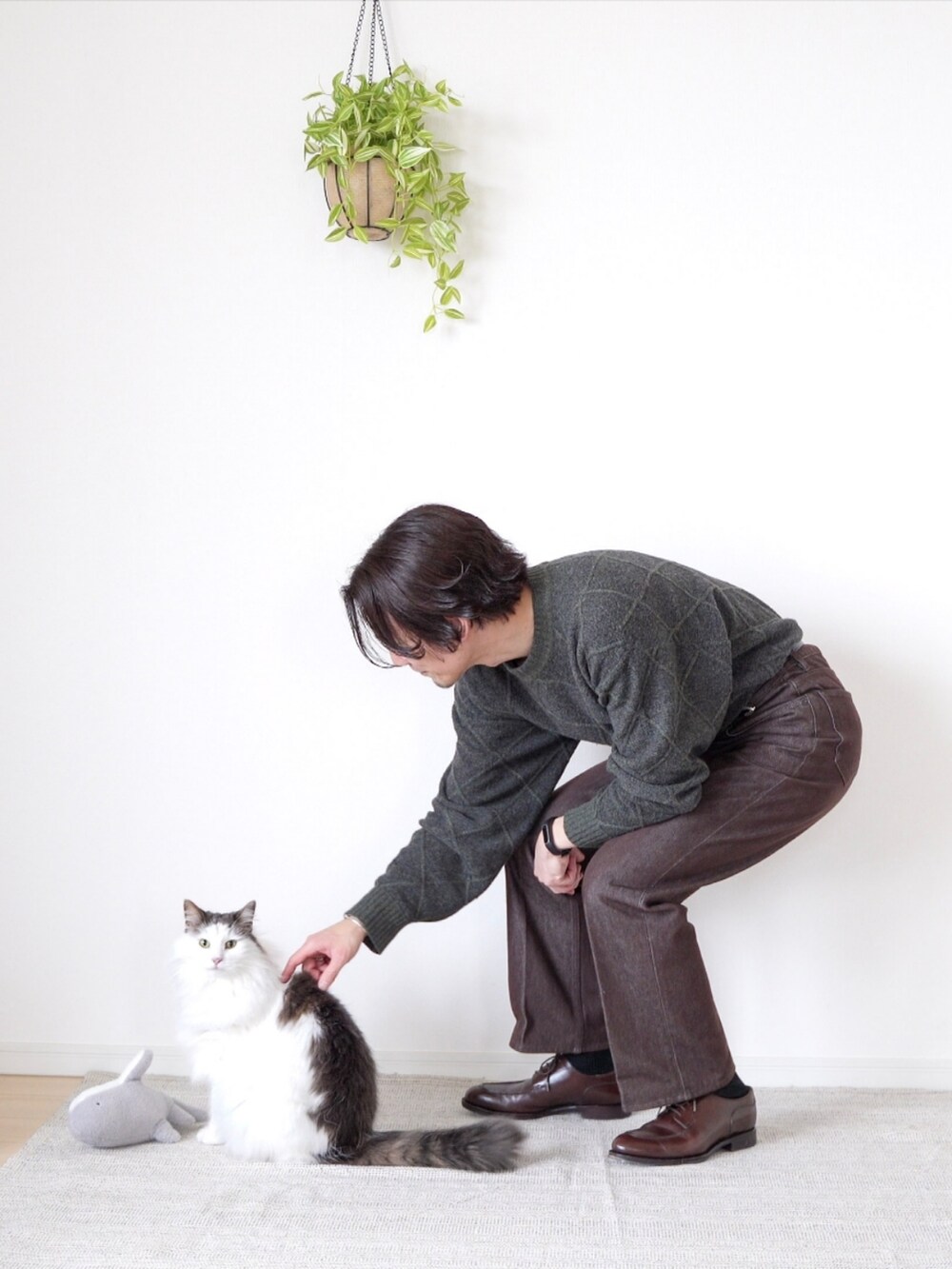 ブラウン系のデニムパンツ、ブラウン系のドレスシューズ、グリーン系のニット/セーターを着用したメンズの冬コーディネートの3枚目の写真