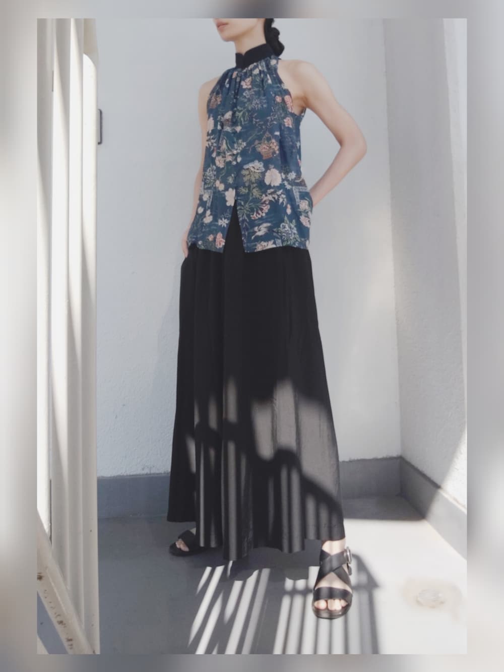 ブルー系のトップス、ブラック系のパンツ、ブラック系のサンダルを着用したレディースの夏コーディネートの2枚目の写真