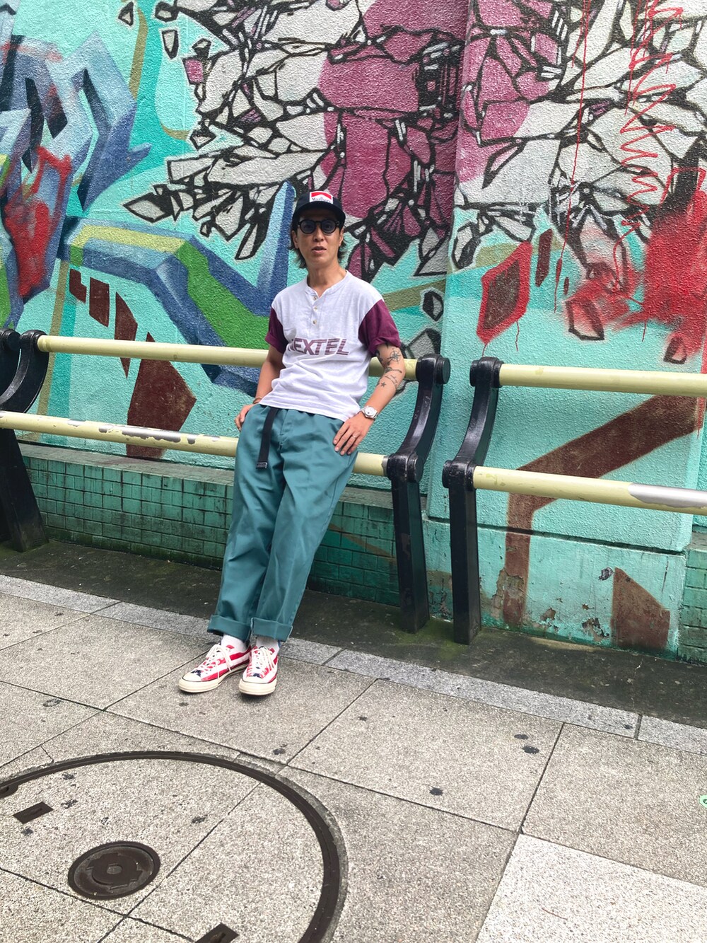 グレー系のTシャツ/カットソー、グレー系のチノパンツ、レッド系のスニーカーを着用したメンズの秋コーディネートの2枚目の写真