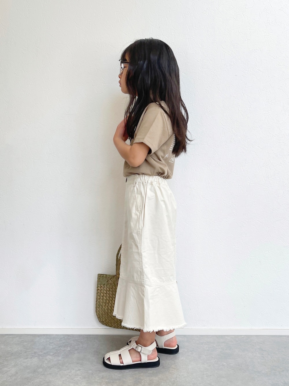 ホワイト系のスカート、ベージュ系のTシャツ/カットソー、ベージュ系のトートバッグを着用したキッズの春コーディネートの3枚目の写真