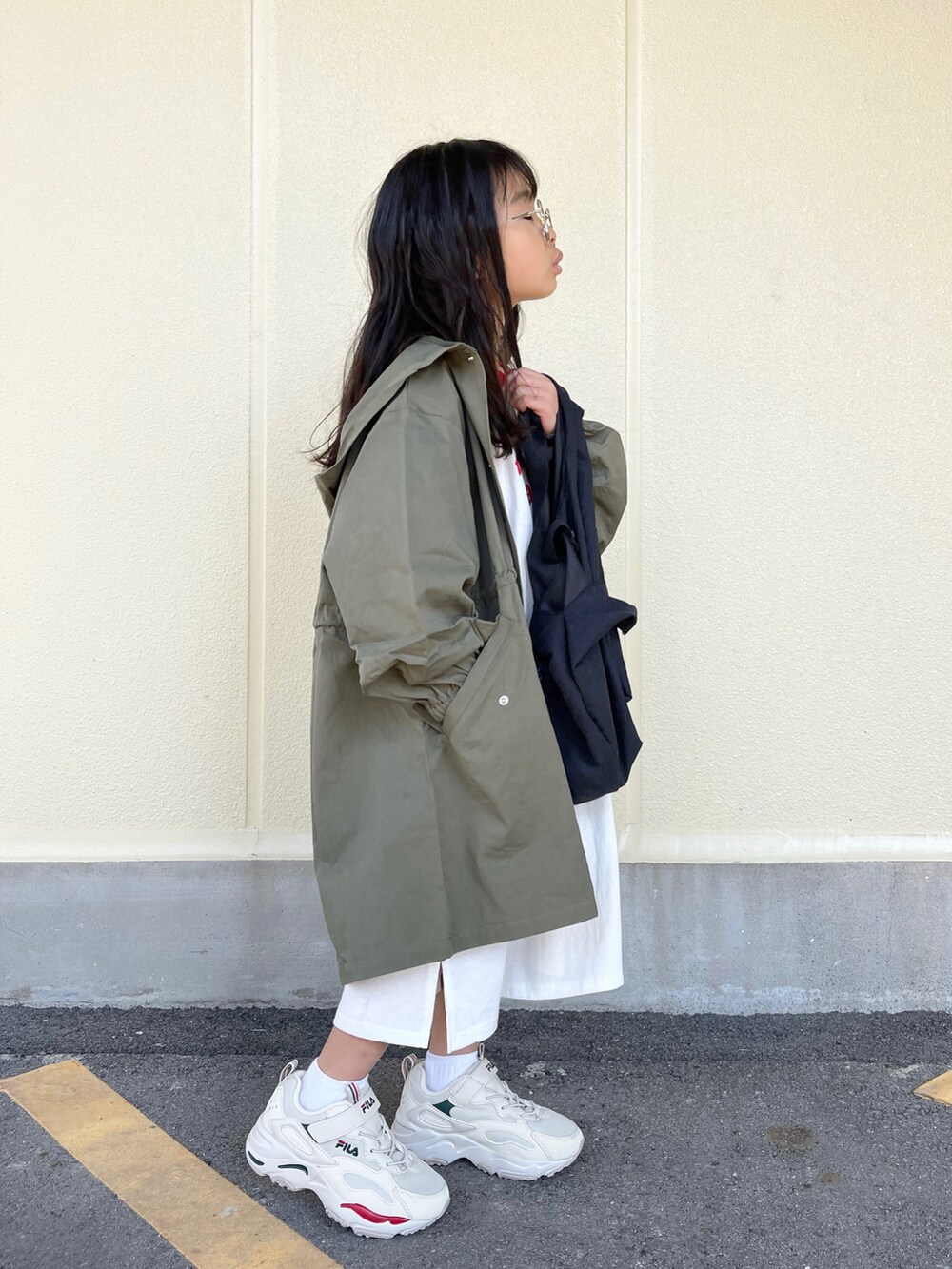 グリーン系のミリタリージャケット、ホワイト系のワンピース、ベージュ系のスニーカーを着用したキッズの春コーディネートの3枚目の写真