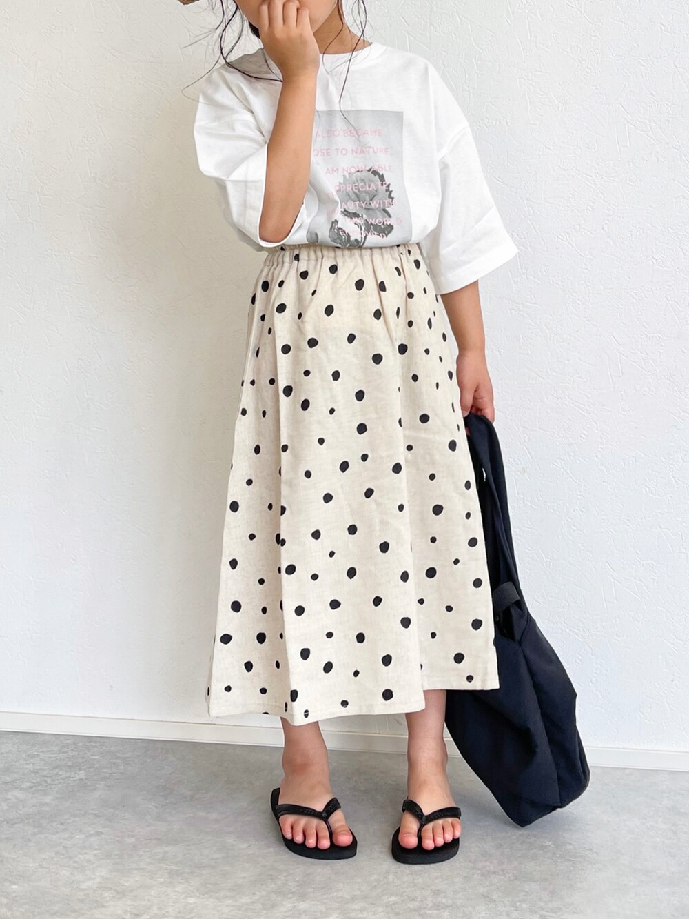ホワイト系のスカート、ホワイト系のTシャツ/カットソー、ブラック系のエコバッグ/サブバッグを着用したキッズの春コーディネートの4枚目の写真