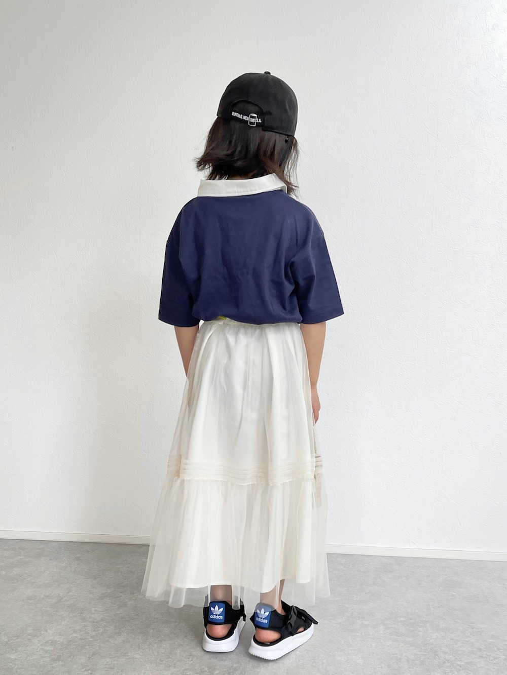 ブルー系のポロシャツ、ホワイト系のスカート、ブラック系のサンダルを着用したキッズの春コーディネートの2枚目の写真