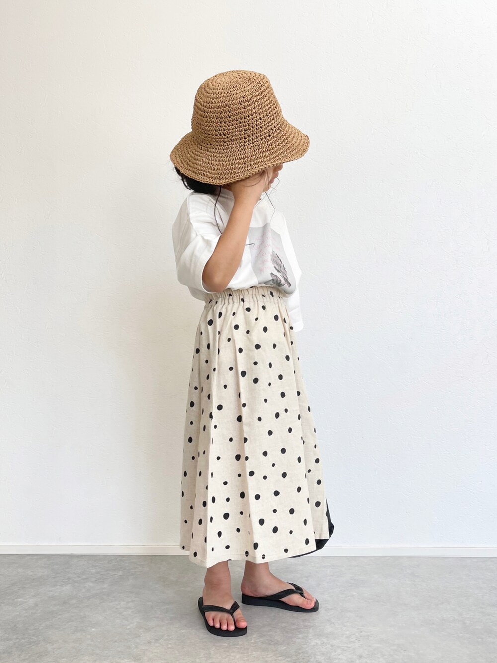 ホワイト系のスカート、ホワイト系のTシャツ/カットソー、ブラック系のエコバッグ/サブバッグを着用したキッズの春コーディネートの2枚目の写真