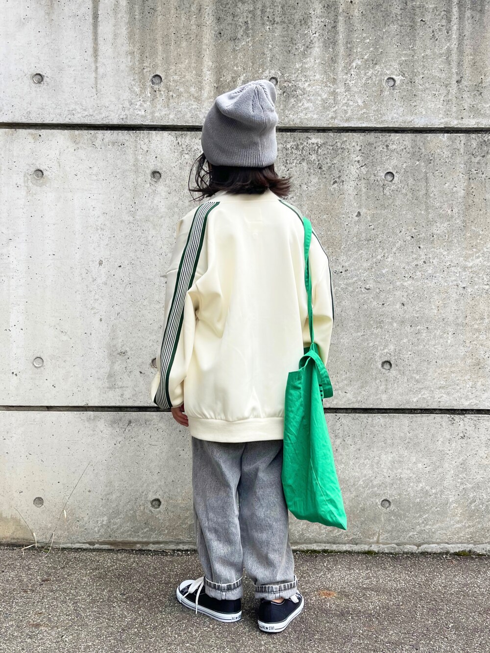 ホワイト系のブルゾン、ブラック系のデニムパンツ、ブラック系のスニーカーを着用したキッズの秋コーディネートの2枚目の写真