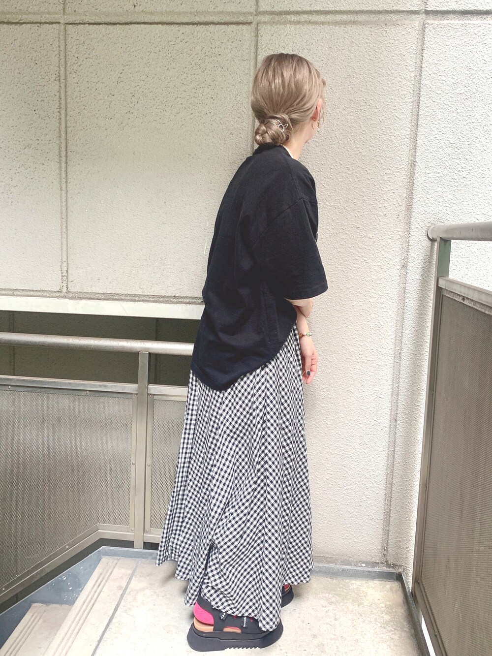 ブラック系のTシャツ/カットソー、ホワイト系のスカート、ブラック系のサンダルを着用したレディースの夏コーディネートの2枚目の写真