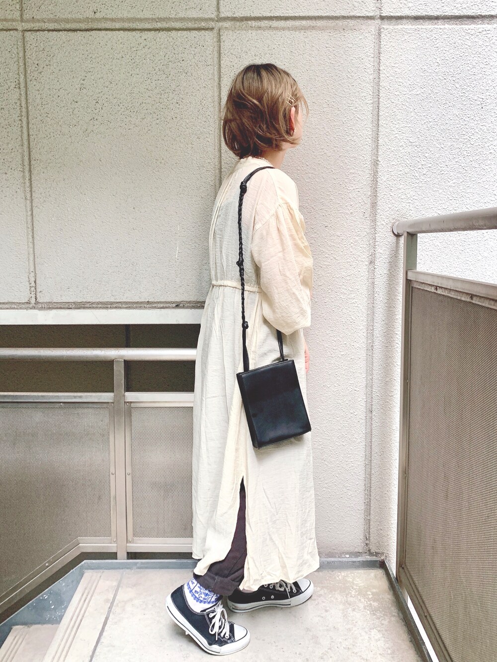 ホワイト系のワンピース、ブラック系のショルダーバッグ、グレー系のデニムパンツを着用したレディースの春コーディネートの2枚目の写真