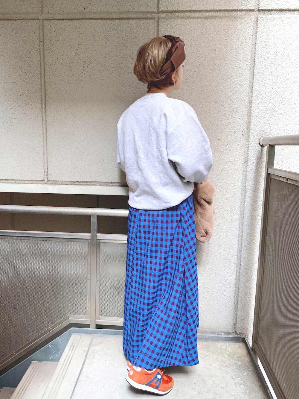 グレー系のスウェット、ブラウン系のハンドバッグ、ブルー系のワンピースを着用したレディースの秋コーディネートの2枚目の写真