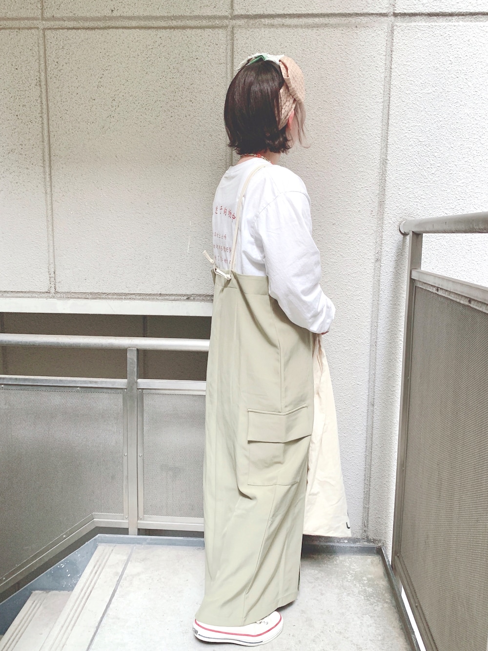 ホワイト系のTシャツ/カットソー、グリーン系のジャンパースカート、ホワイト系のエコバッグ/サブバッグを着用したレディースの春コーディネートの2枚目の写真