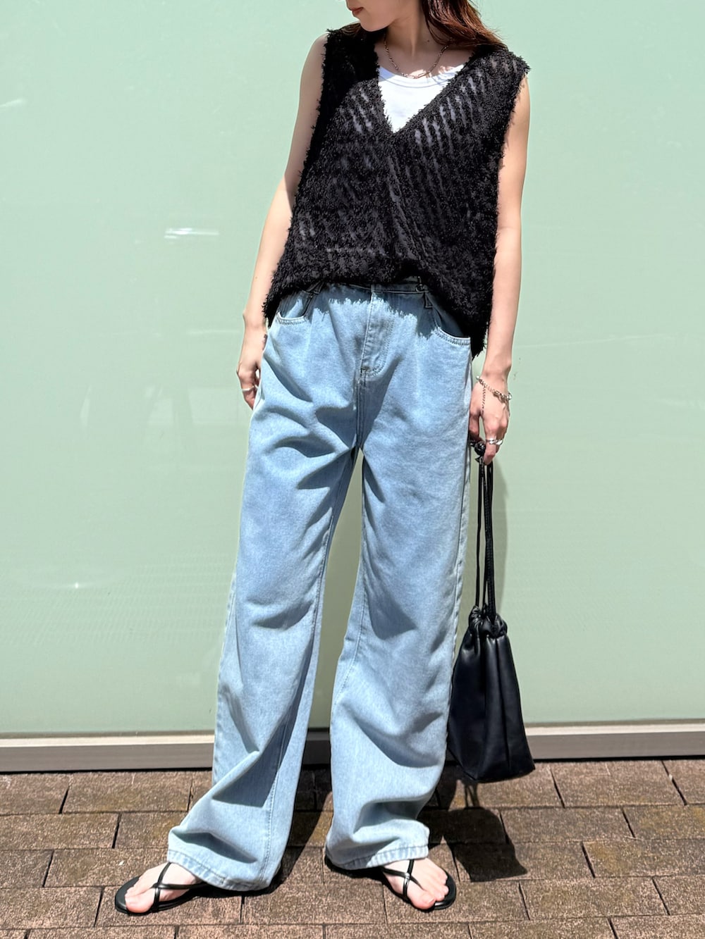 ブラック系のタンクトップ、ホワイト系のタンクトップ、ブルー系のデニムパンツを着用したレディースの春コーディネートの3枚目の写真