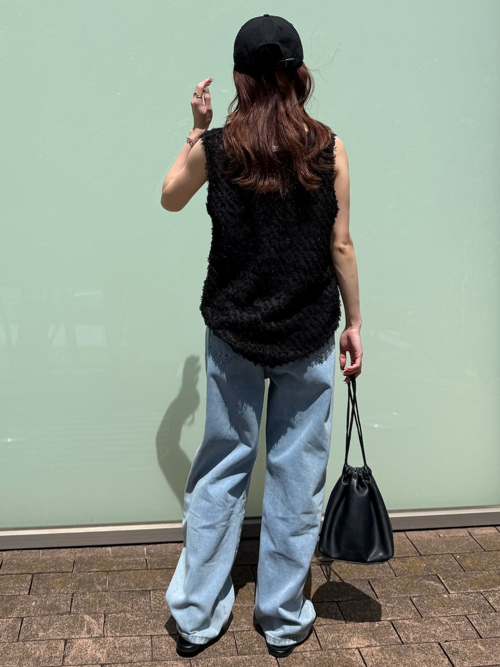 ブラック系のタンクトップ、ホワイト系のタンクトップ、ブルー系のデニムパンツを着用したレディースの春コーディネートの4枚目の写真