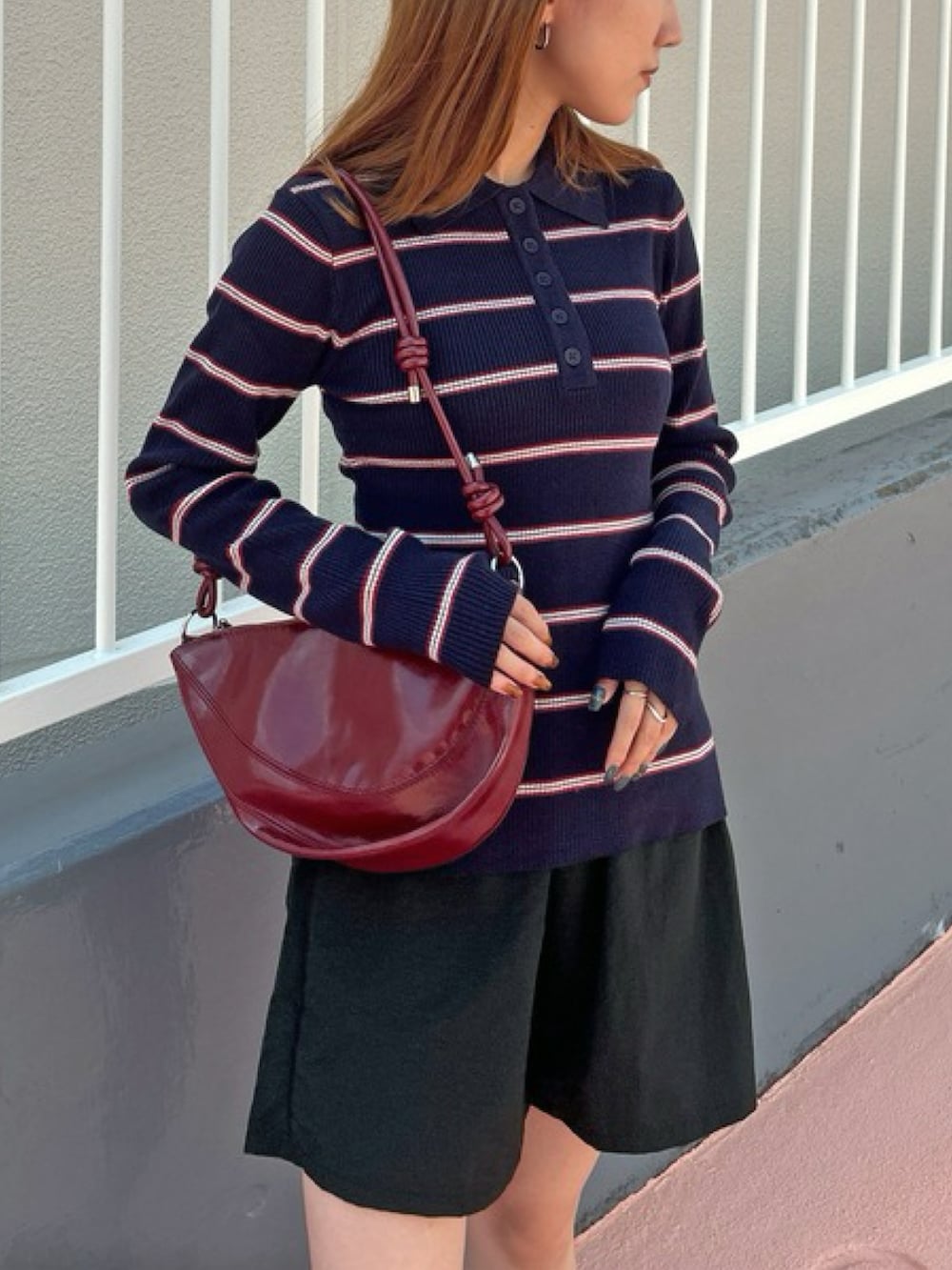 ブルー系のニット/セーター、ブラック系のセットアップ、レッド系のハンドバッグを着用したレディースの秋コーディネートの2枚目の写真