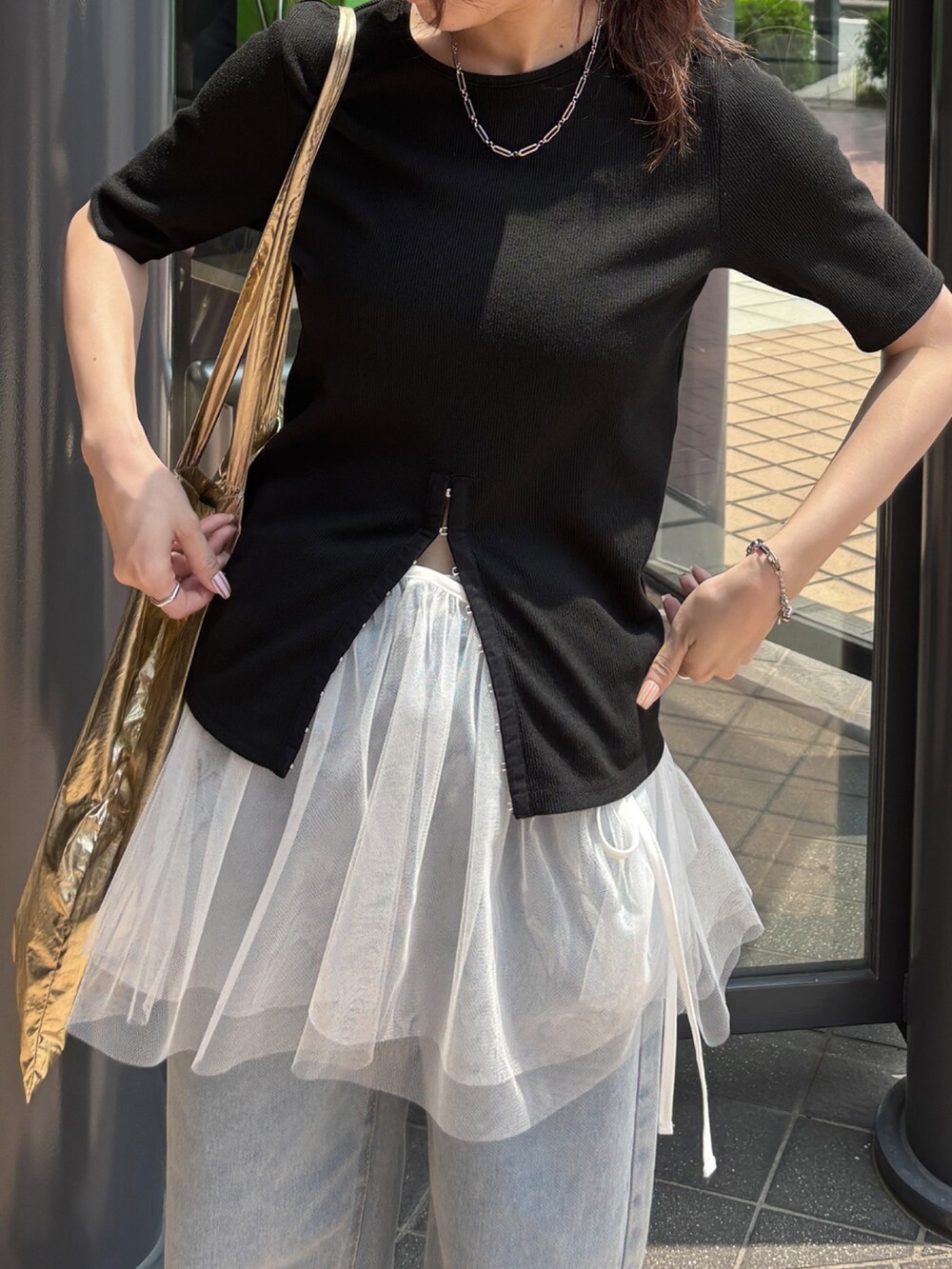 ブラック系のTシャツ/カットソー、ブルー系のデニムパンツ、ホワイト系のスカートを着用したレディースの秋コーディネートの2枚目の写真