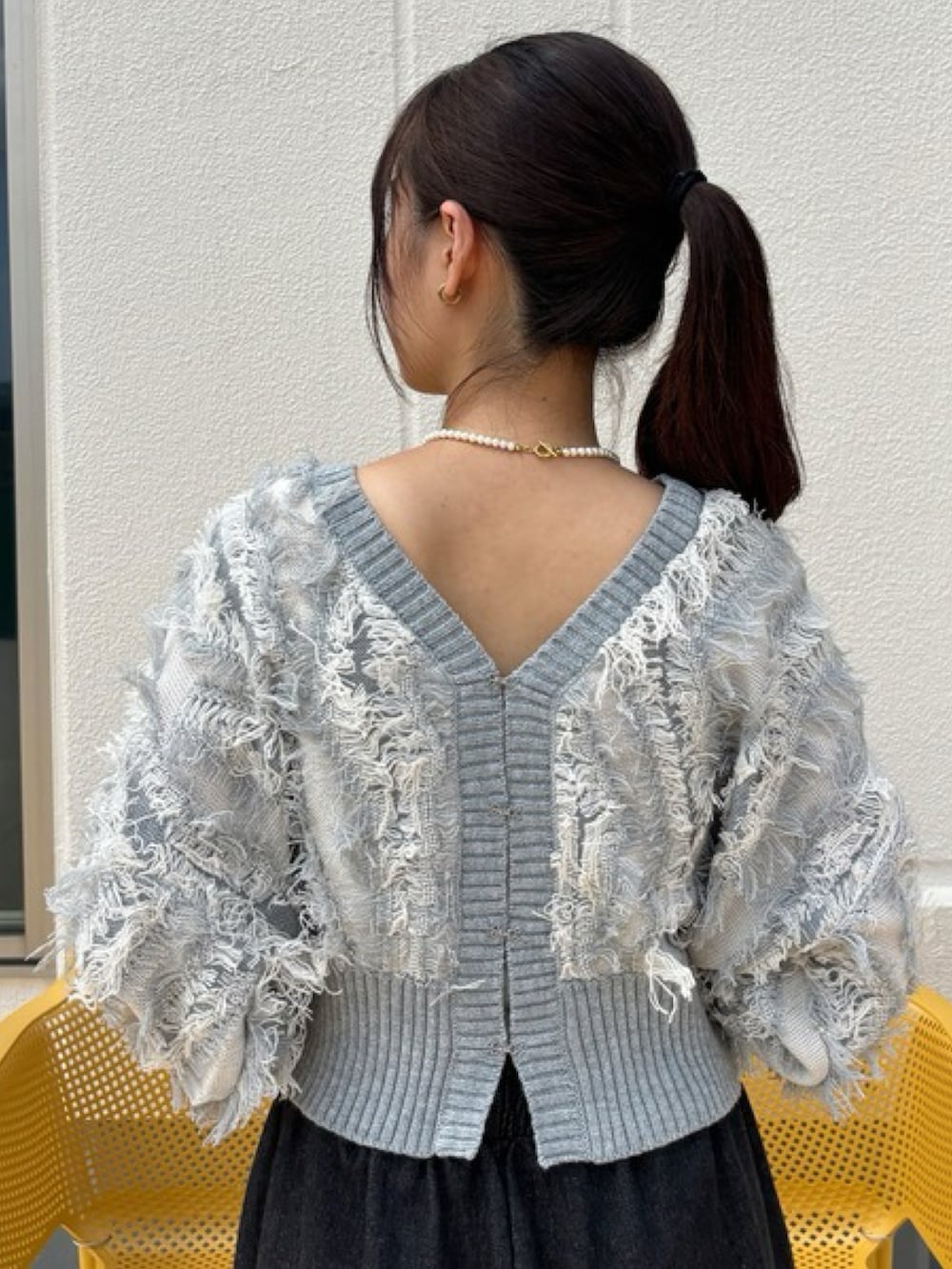 グレー系のニット/セーター、ブラック系のデニムパンツ、ブラック系のスニーカーを着用したレディースの秋コーディネートの2枚目の写真