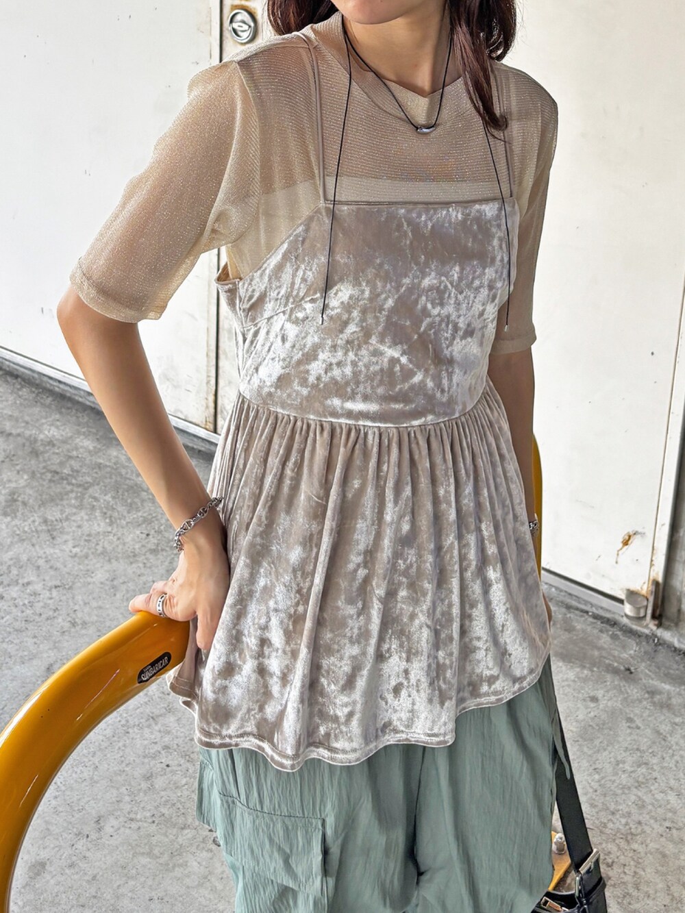 ベージュ系のキャミソール、グリーン系のカーゴパンツ、ゴールド系のTシャツ/カットソーを着用したレディースの夏コーディネートの2枚目の写真