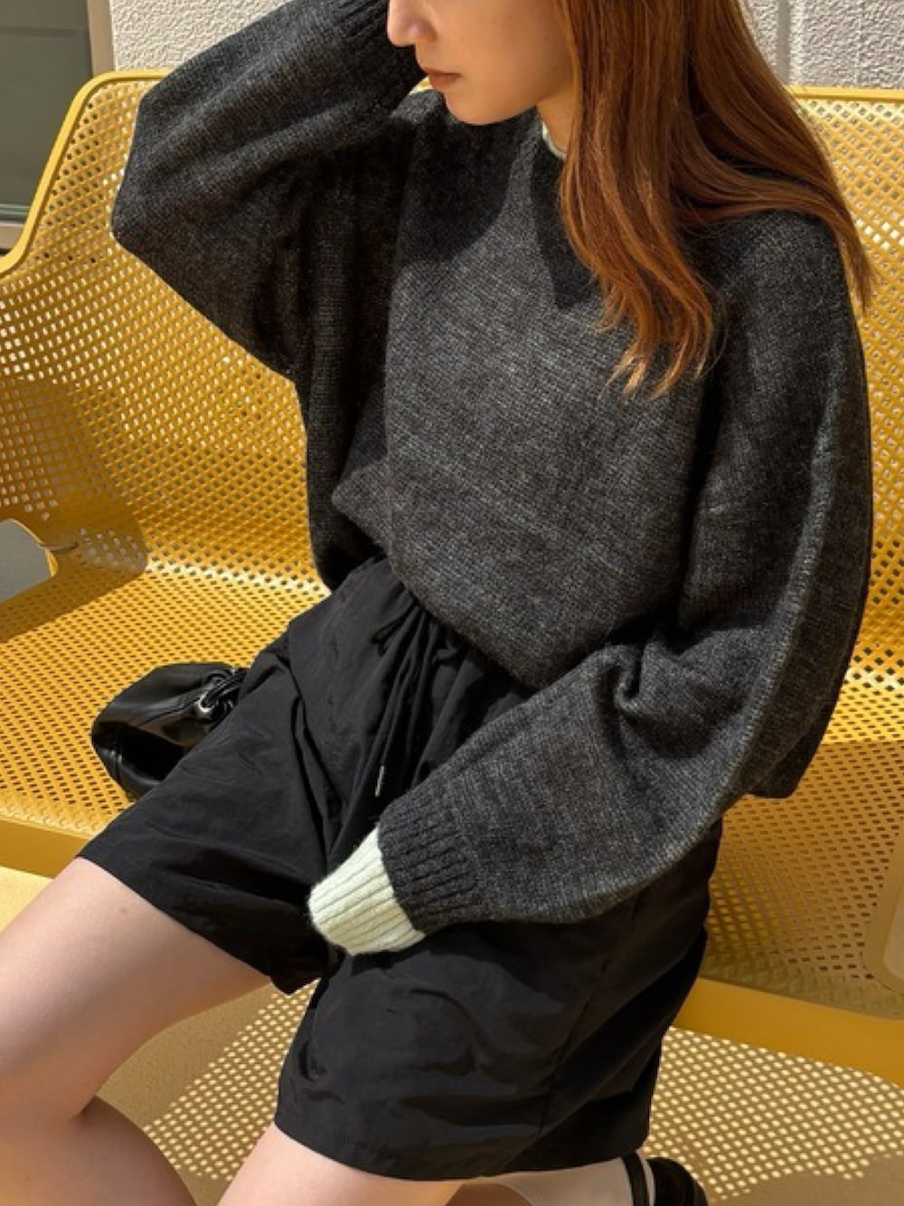 グレー系のニット/セーター、ブラック系のセットアップを着用したレディースの秋コーディネートの2枚目の写真