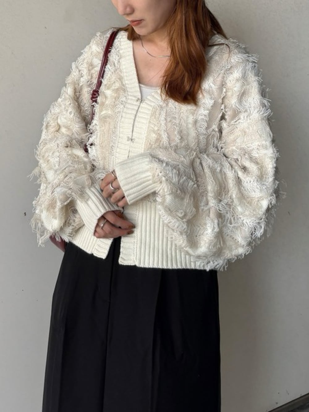 ホワイト系のニット/セーター、レッド系のハンドバッグ、ブラック系のスカートを着用したレディースの秋コーディネートの2枚目の写真