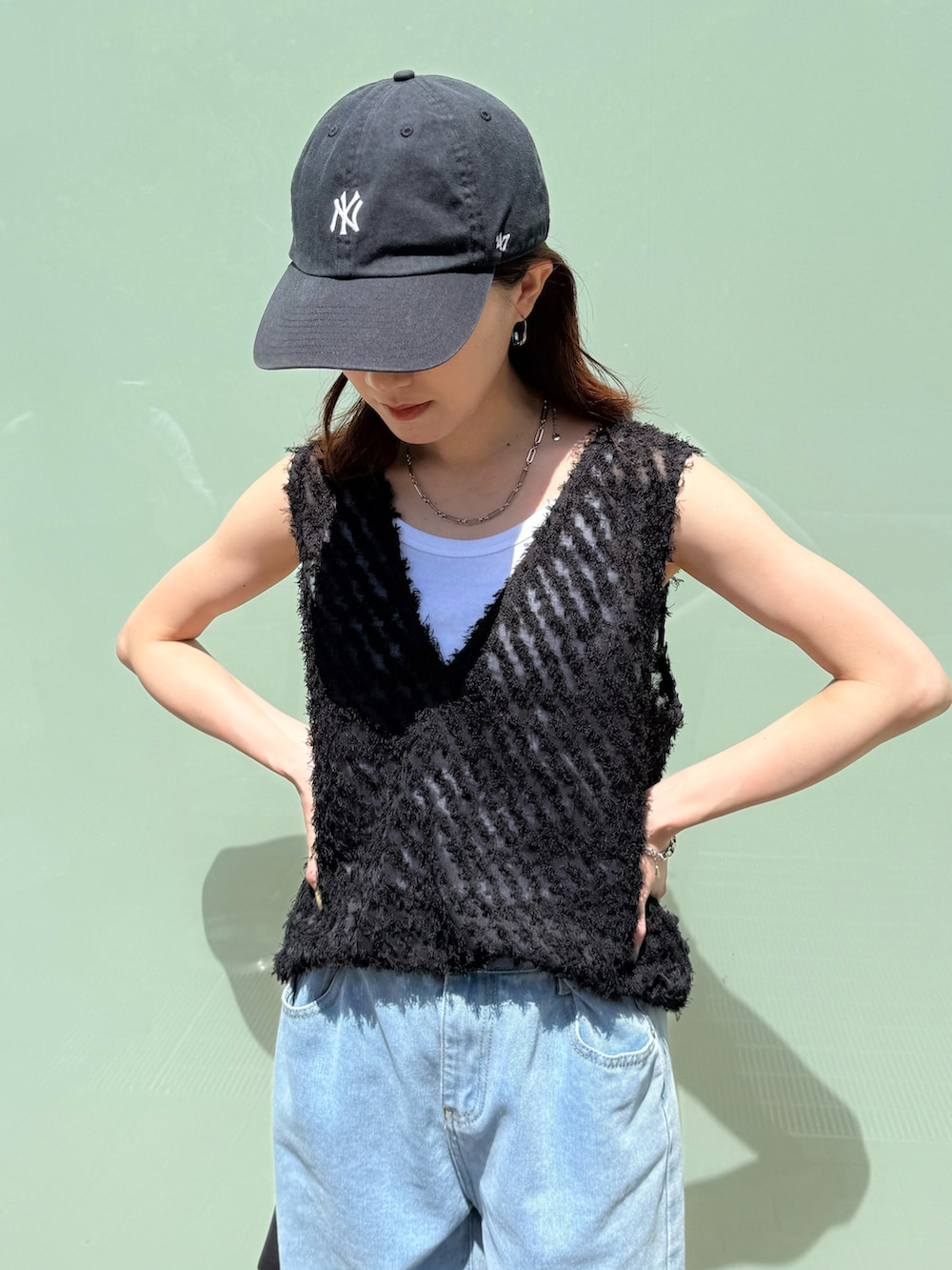 ブラック系のタンクトップ、ホワイト系のタンクトップ、ブルー系のデニムパンツを着用したレディースの春コーディネートの2枚目の写真