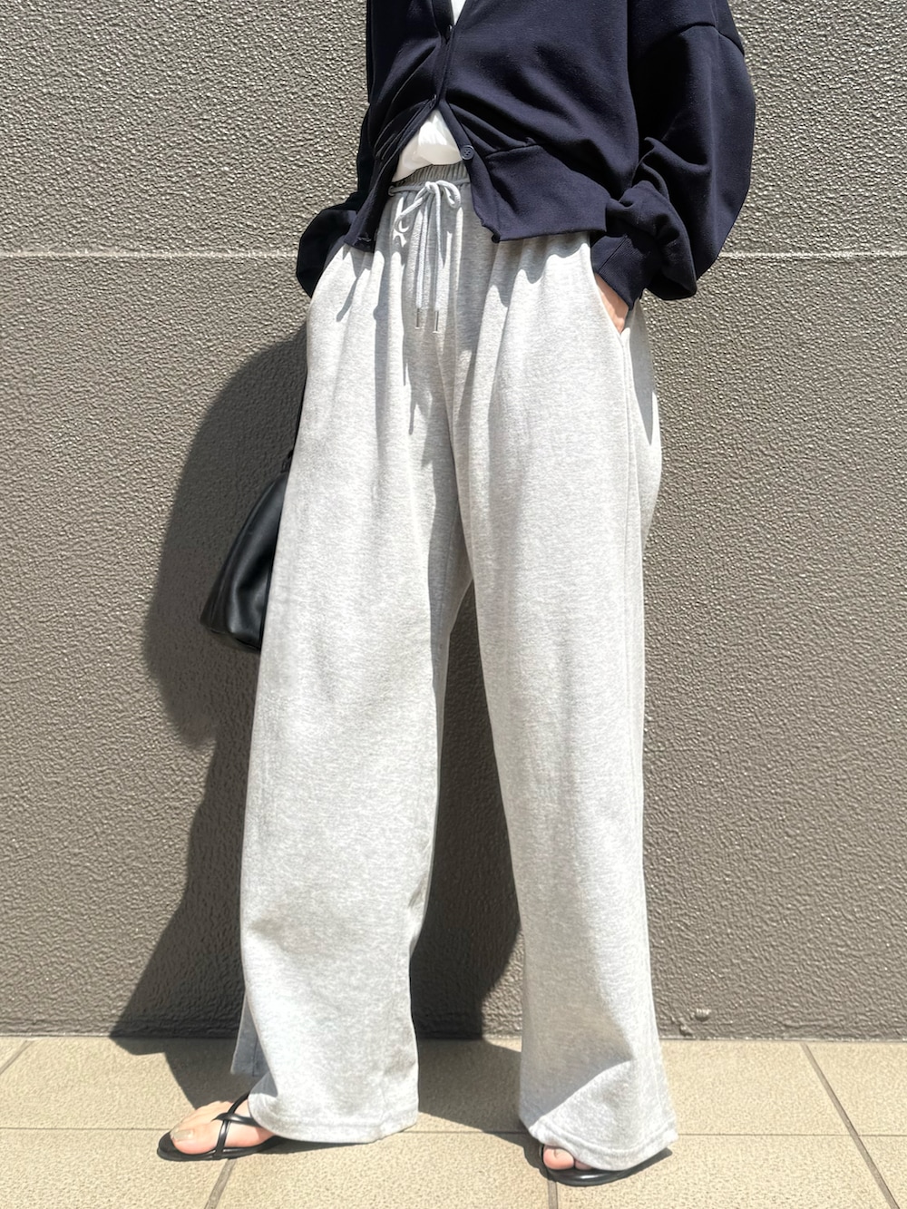 グレー系のスウェットパンツ、ブルー系のカーディガン/ボレロ、ホワイト系のチュニックを着用したレディースの春コーディネートの2枚目の写真